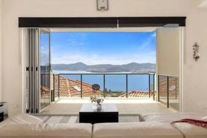 The View Sandy Bay 5 bedroom في هوبارت: غرفة معيشة مع أريكة وإطلالة على المحيط