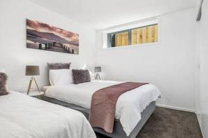 a white bedroom with two beds and a window at Residence at 165 Great for large groups Sleeps 11 in Hobart