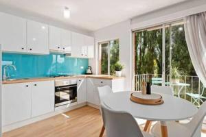 cocina con mesa blanca y sillas blancas en Renovated unit in leafy surrounds close to shops, en Hobart