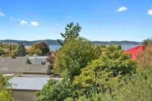 a group of houses and trees with a body of water at Renovated unit in leafy surrounds close to shops in Hobart