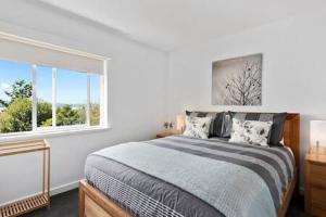een slaapkamer met een groot bed en een raam bij Renovated unit in leafy surrounds close to shops in Hobart