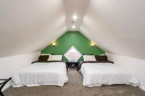 two beds in a room with a green wall at Housepitality - The Mint Julep House in Columbus +11 photos