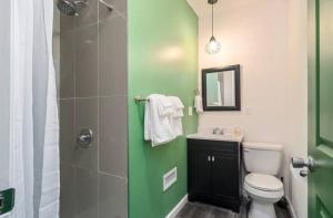 uma casa de banho verde e branca com um WC e um chuveiro em Housepitality - The Mint Julep House em Columbus