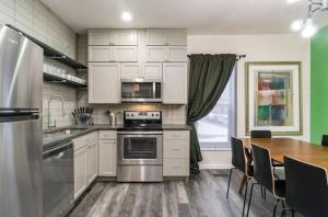 uma cozinha com armários brancos, uma mesa e um fogão em Housepitality - The Mint Julep House em Columbus
