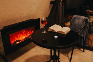 a glass of wine and a book on a table next to a fireplace at Rose Valley Cottage in Ieriķi +12 photos