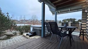 um deque com uma mesa, cadeiras e comodidades para churrascos em Laakson Helmi 2 ,separate sauna, fireplace, lake em Himos