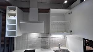uma cozinha com armários brancos e um lavatório em Laakson Helmi 2 ,separate sauna, fireplace, lake em Himos
