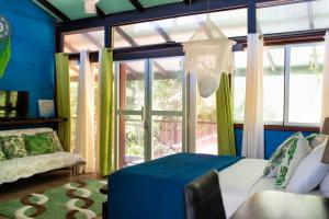 ein Schlafzimmer mit einem Bett und einem großen Fenster in der Unterkunft Coyote Rooms in Cabuya