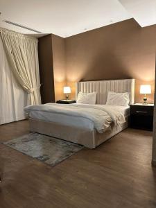 a bedroom with a large bed and two lamps on tables at full luxury one bed apartment with maid room penta square in Lahore