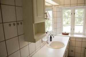 a white bathroom with a sink and two windows at The Mill House - Saeby Watermill in Sæby