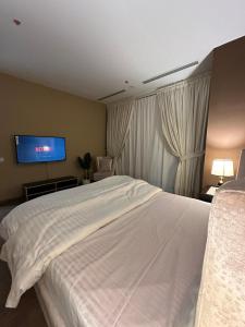 a bedroom with a white bed and a flat screen tv at full luxury one bed apartment with maid room penta square in Lahore