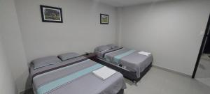 Habitación con 2 camas y 2 cuadros en la pared. en Suite en el centro de Moyobamba en Moyobamba