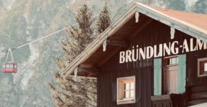 ein Gebäude mit einem Schild neben einem Berg in der Unterkunft Bründling-Alm Berggasthof auf 1167m auf dem Hochfelln in Bergen