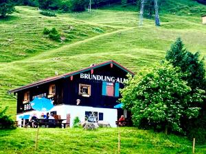 a building with people sitting outside of it on a hill at Bründling-Alm Berggasthof auf 1167m auf dem Hochfelln in Bergen +17 photos