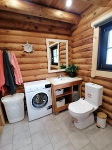 a bathroom with a toilet and a washing machine in a log cabin at Tirtsu puhkemaja 