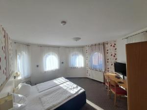 a bedroom with a bed and a desk and two windows at Gasthof Hirschkeller in Göppingen