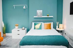 a bedroom with blue walls and a bed with pillows at Vibrant Studio Close to Anfield Stadium in Liverpool