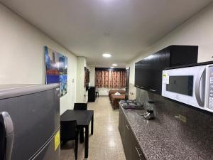 a room with a kitchen with a microwave and a living room at Residencia Terreros in Guayaquil