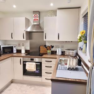 a kitchen with white cabinets and a stove top oven at Impeccable 2-Bed House in Coventry in Coventry