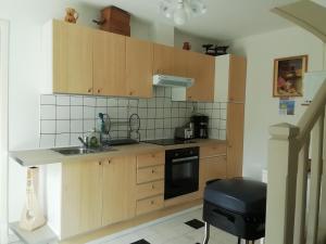 a kitchen with wooden cabinets and a sink and a stove at Gîtes de la chapelette in Péronne