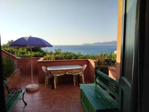 a patio with an umbrella and a table and benches at MAREVIGLIOSO Fronte Mare Sea Front in Magomadas
