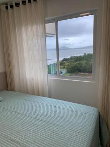 1 dormitorio con cama y ventana en BALI BEACH HOME CLUB Piçarras, en Piçarras