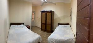 マルサ・マトルーフにあるAlmanara Hotel Marsa Matrouhのベッド2台と木製キャビネットが備わる客室です。
