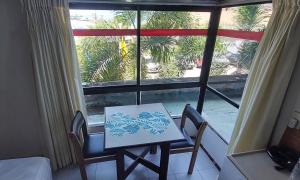 einen Tisch und Stühle in einem Zimmer mit Fenster in der Unterkunft Apart-Hotel em Tambaú - Super Central com Vista Mar - Ap.113 in João Pessoa