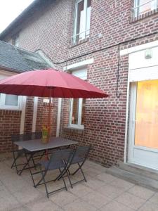 a picnic table with a red umbrella in front of a brick building at Gîtes de la chapelette in Péronne