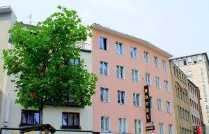Boutique 003 Köln am DOM في كولونيا: مبنى وردي امامه شجرة