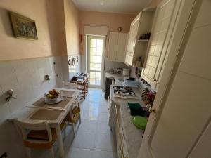a kitchen with white cabinets and a table with a bowl of fruit at Central House in Castel di Sangro