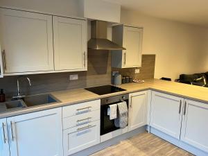 een keuken met witte kasten en een wastafel bij Inchcailloch Townhouse, Loch Lomond in Bonhill