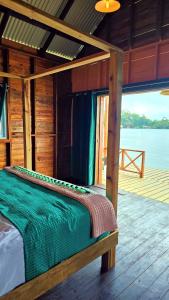 a bed in a cabin with a view of the water at The Sea Monkey in Bocas del Toro