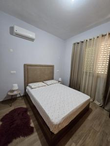 a bedroom with a bed and a window with curtains at Apart Nel in Praia