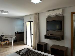 Habitación con cama y TV en la pared. en Flat 1209 - Conforto Parque Areião, en Goiânia