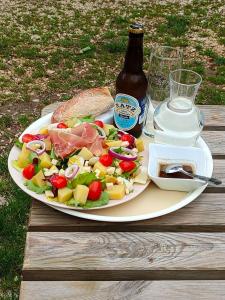a plate of food with a salad and a bottle of beer at CAMPING LE BEL AIR Mobil home L'OLIVIER 4 personnes in Limogne-en-Quercy