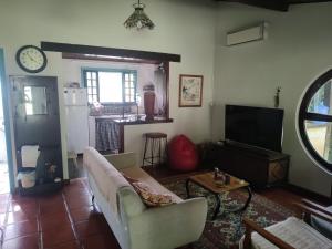 sala de estar con sofá y TV en Chalé em Itaocaia Valley Itaipuaçu Maricá RJ, en Maricá