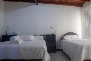 1 Schlafzimmer mit 2 Betten und weißer Bettwäsche in der Unterkunft Casa Calas in Alajuela