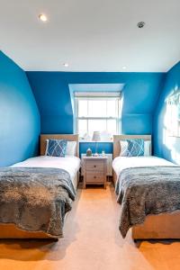 two beds in a room with blue walls at Entire 2 Bed Flat Contractors Families and Relocators in Ware
