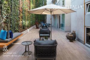 a patio with an umbrella and chairs and a table at Capitalia - ApartHotel - San Angel Inn in Mexico City