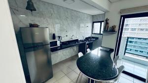 a kitchen with a black table and a refrigerator at Apartamento com varanda in Guarujá