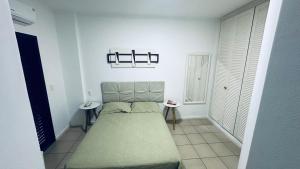 a small bedroom with a bed and two tables at Apartamento com varanda in Guarujá +7 photos