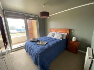 Un dormitorio con una cama azul y una ventana en Hermoso Departamento en Puerto Montt, en Puerto Montt