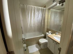 Baño blanco con aseo y lavamanos en Hermoso Departamento en Puerto Montt, en Puerto Montt