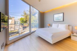 een slaapkamer met een wit bed en een groot raam bij Capitalia San Angel Inn in Mexico-Stad