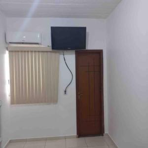 a room with a door and a tv on a wall at Casa de Veraneio IOS in Ilhéus