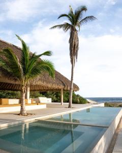 a swimming pool at a resort with two palm trees at Mazul Puerto Escondido in Tlachicón