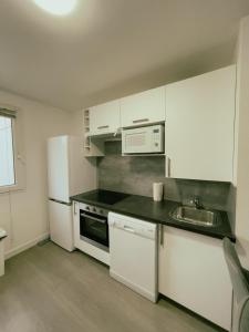 eine Küche mit weißen Schränken und einem Waschbecken in der Unterkunft Appartement Proche U Arena et La Défense in Nanterre