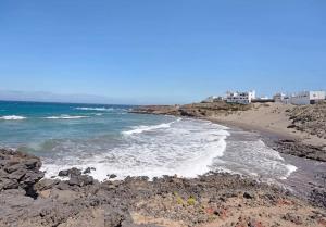 a beach with rocks and the ocean and buildings at Poris puesta de sol 2 in Santa Cruz de Tenerife