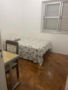 a bedroom with a bed and a table and a window at Apartamento Praça da Liberdade in Belo Horizonte